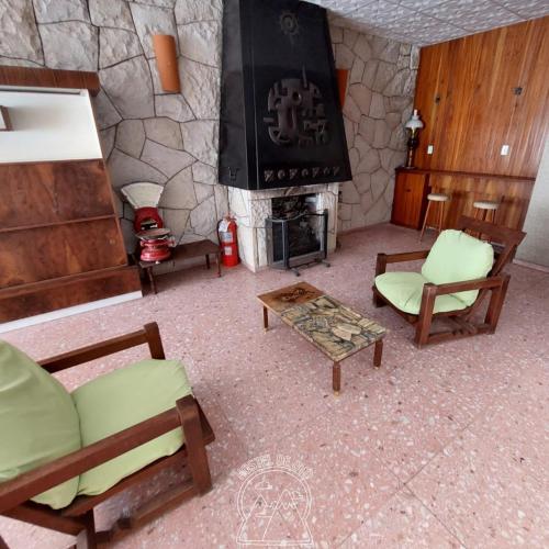 a living room with a stone fireplace and chairs at Hostel De Oto in Godoy Cruz