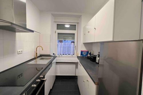 a white kitchen with a sink and a refrigerator at DE Apartment in Neu Ulm