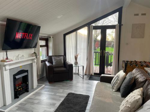 a living room with a tv above a fireplace at Cosy 3 Bed Lodge in Hoburne, Cotswolds in South Cerney
