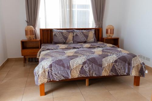 Shalom Villas في Mamobi: غرفة نوم مع سرير مع لحاف أرجواني
