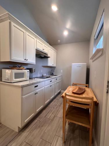 a kitchen with white cabinets and a wooden table at Private modern guesthouse, near La Cantera/Medical Center in San Antonio