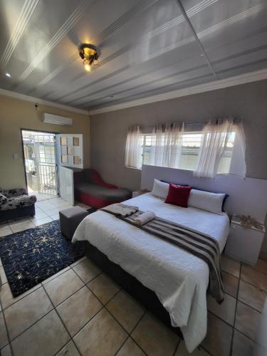 a bedroom with a large bed and a red couch at Tshedza Guest House in Pretoria