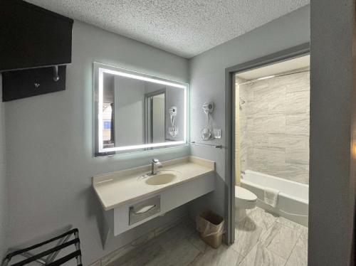 een badkamer met een wastafel, een toilet en een spiegel bij Motel 6 Chickasha, OK in Chickasha