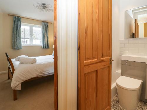 a bathroom with a bedroom with a bed and a toilet at Maple Cottage in Broadway