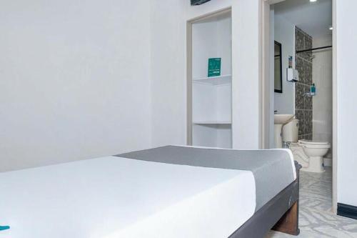 a white bedroom with a bed and a bathroom at Hotel Confort Boutique in Rionegro
