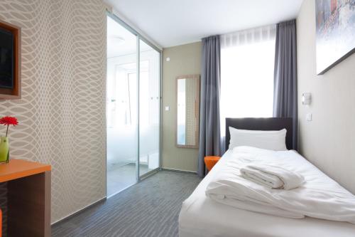 a bedroom with a white bed and a glass shower at Stay-Inn Bielefeld Zentrum in Bielefeld