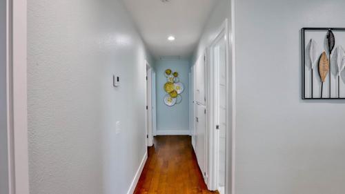 a hallway of a home with white walls and wood floors at H&H Modern Lux 4BD 1 King Suite 3 Queen SoCal Disney in Westminster