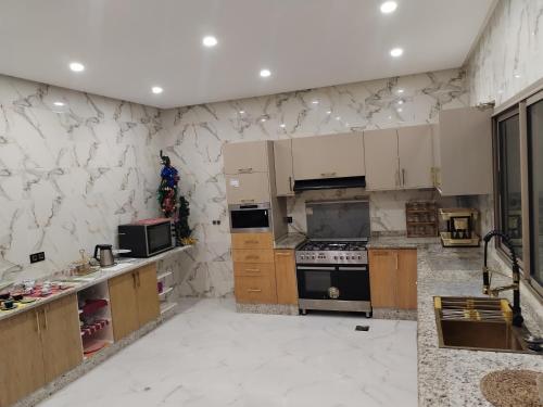 a kitchen with white marble walls and wooden cabinets at شقة رائعة داخل فيلا مستقلة in Casablanca