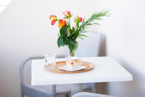 a table with two cups of coffee and a vase of flowers at Kronos Hotel in Heraklio Town