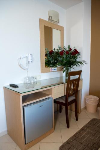 a desk with a mirror and a vase of red roses at Kronos Hotel in Heraklio Town