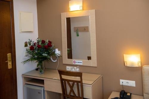 a room with a table with a vase of flowers and a mirror at Kronos Hotel in Heraklio Town