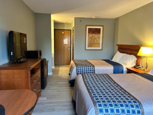 a hotel room with two beds and a flat screen tv at Royal Inn Suites in Huntington