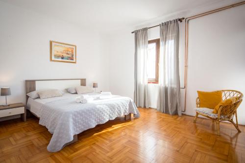 a white bedroom with a bed and a chair at Apartments Luce in Rovinj