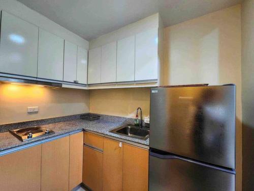 eine Küche mit einem Kühlschrank aus Edelstahl und einer Spüle in der Unterkunft Cozy condo unit at The Palladium in Iloilo City