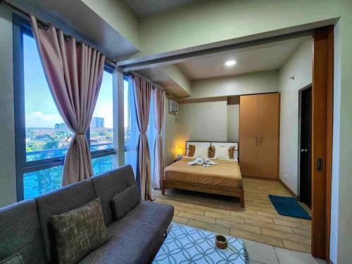 ein Schlafzimmer mit einem Bett und einem großen Fenster in der Unterkunft Cozy condo unit at The Palladium in Iloilo City
