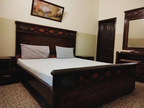 een slaapkamer met een groot bed met een houten hoofdeinde bij Four Season 1 Airport Guest House in Karachi