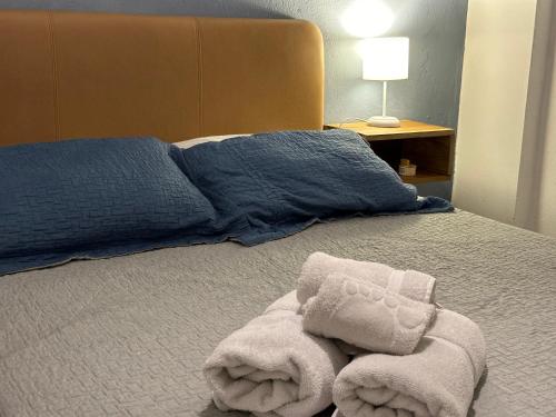a bed with two blue pillows and towels on it at Hotel Casa Lucca in Medellín