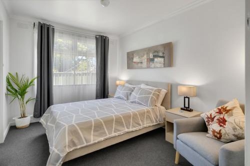 a white bedroom with a bed and a chair at No.8 - One bedroom retreat in central Bendigo in Bendigo