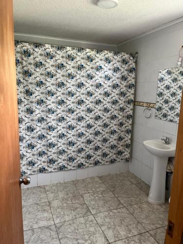baño con cortina de ducha con motivos florales y lavamanos en Hostal Renacer, en Santa Cruz