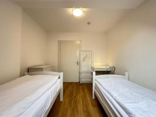 two beds in a small room with a hallway at Cleo Apartments in Kassel