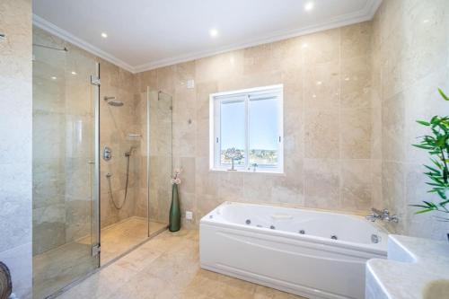 een badkamer met een bad, een douche en een wastafel bij Casa Ferrel - Luxury 9 Bedroom Villa with Indoor & Outdoor Pools in Lagos