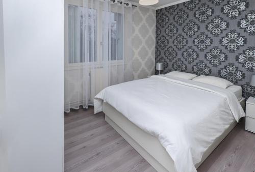 una camera con un letto bianco e un muro di Appartement moderne, proche du Parc de la tête d'Or et de Lyon a Villeurbanne