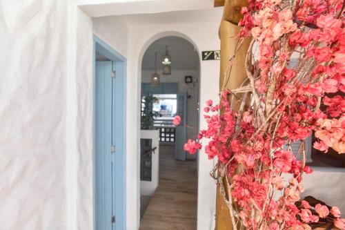 un couloir avec des fleurs roses sur un mur dans l'établissement Vila DuJu, à Porto de Galinhas