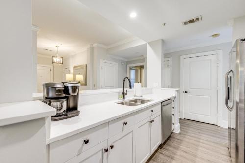 uma cozinha branca com um lavatório e um frigorífico em Chic Greensboro Condo with Lake Oconee Access! em Greensboro