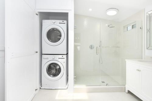 a white laundry room with a washer and dryer at 6 Bedroom Remodeled Home on the Oceanfront in Newport Beach