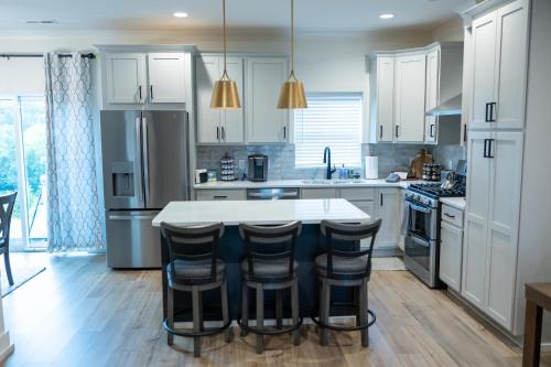 a kitchen with white cabinets and a island with bar stools at New Modern Style Townhome in Sevierville