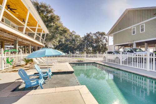 a pool with two chairs and an umbrella next to a house at Walk to Beach Stunning Gulfport Getaway in Gulfport