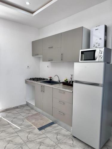 a kitchen with white cabinets and a white refrigerator at Dyar Amina in Midoun