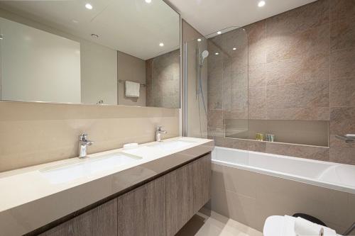 a bathroom with two sinks and a tub and a mirror at Burj Khalifa View, High Floor, Dubai Mall Access, Gym, Infinity-Pool, Playground, BBQ, Family Friendly in Dubai
