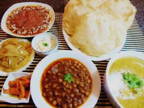 a table with plates of food with beans and bread at Four Season 1 Airport Guest House in Karachi