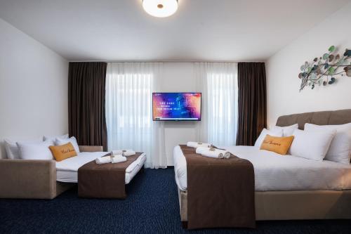 um quarto de hotel com duas camas e um sofá em Hotel Šumava em Železná Ruda