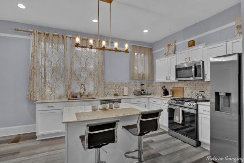 a kitchen with white cabinets and a island with bar chairs at Renovated, Spacious, Historic. in Shreveport