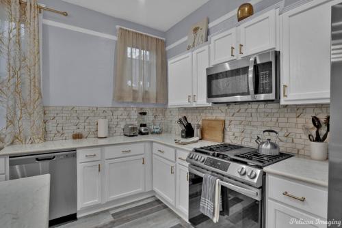 a kitchen with white cabinets and a stove and microwave at Renovated, Spacious, Historic. in Shreveport