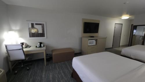 a hotel room with a bedroom with a bed and a desk at West Valley Inn in West Valley City