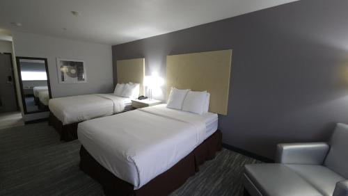 a hotel room with two beds and a couch at West Valley Inn in West Valley City