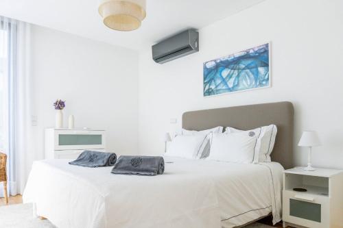 a white bedroom with a white bed with white pillows at Beach & Garden Apartment in Ponta Delgada