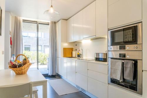 a kitchen with white cabinets and a table and a microwave at Beach & Garden Apartment in Ponta Delgada