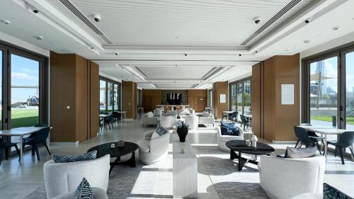a lobby with white chairs and tables and windows at Burj Khalifa View, High Floor, Dubai Mall Access, Gym, Infinity-Pool, Playground, BBQ, Family Friendly in Dubai