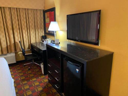 a hotel room with a desk with a flat screen tv at Ramada by Wyndham Rochelle Park Near Paramus in Rochelle Park