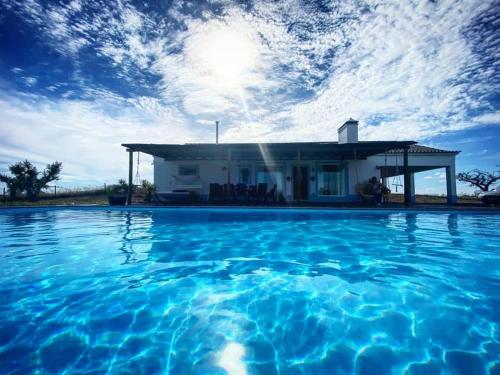 a swimming pool with a house in the background at Monte Das 7 Oliveiras in Pias