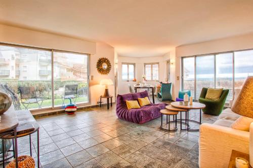 un salon avec un canapé, des chaises et des fenêtres dans l'établissement Les Terrasses - Vue Mer - Tourgéville, à Tourgéville