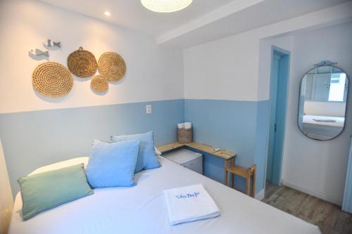 a bedroom with a white bed with blue pillows and a mirror at Vila DuJu in Porto De Galinhas