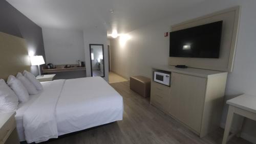 a hotel room with a bed and a flat screen tv at West Valley Inn in West Valley City