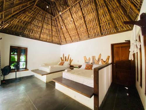 a bedroom with two beds and a straw roof at Pacifico El Paredon in El Paredón Buena Vista