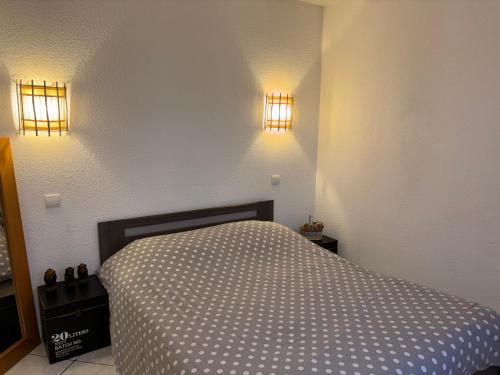 a bedroom with a bed and two lights on the wall at Les clés de Jonzac-conciergerie Nid de Douceur in Ozillac