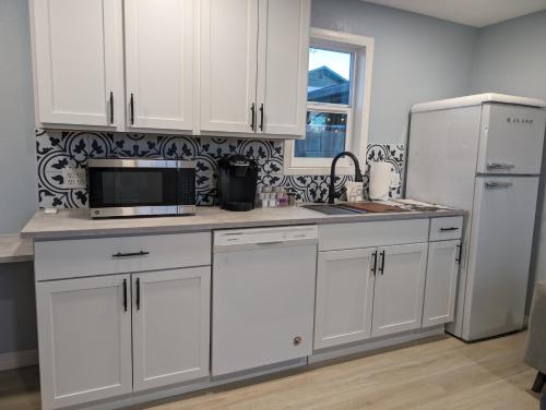 eine Küche mit weißen Schränken, einer Mikrowelle und einem Kühlschrank in der Unterkunft Chic Parisian Guest House in Phoenix